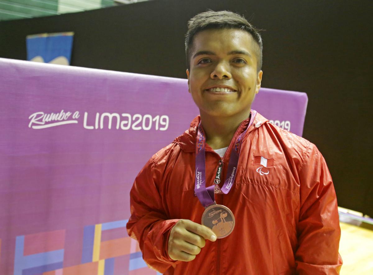 Diego Quispe smiles while he holds the bronze medal he won at the Lima World Cup