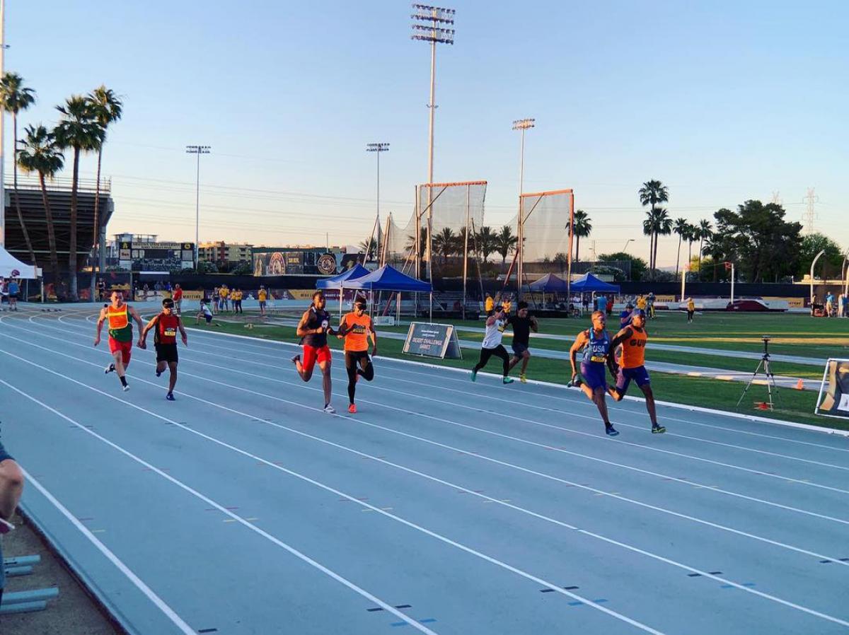 Four male vision impaired runners and thir guides racing on a track