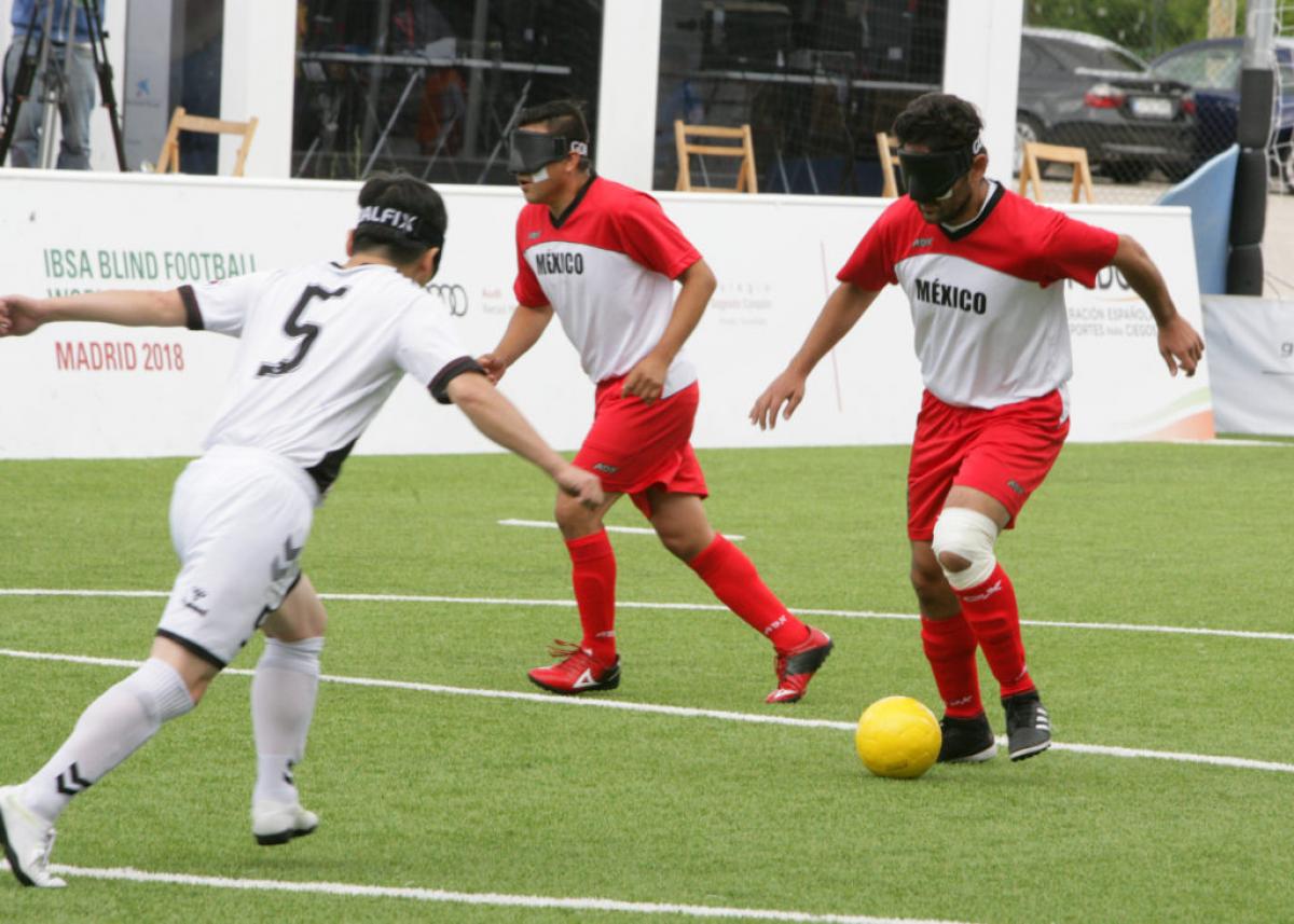 Mexican blind football player Jorge Lanzagorta controls the ball and faces South Korean defender