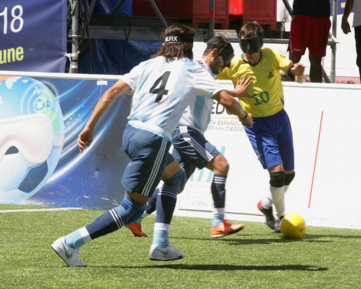 Ricardinho takes the ball while facing two Argentinian defenders
