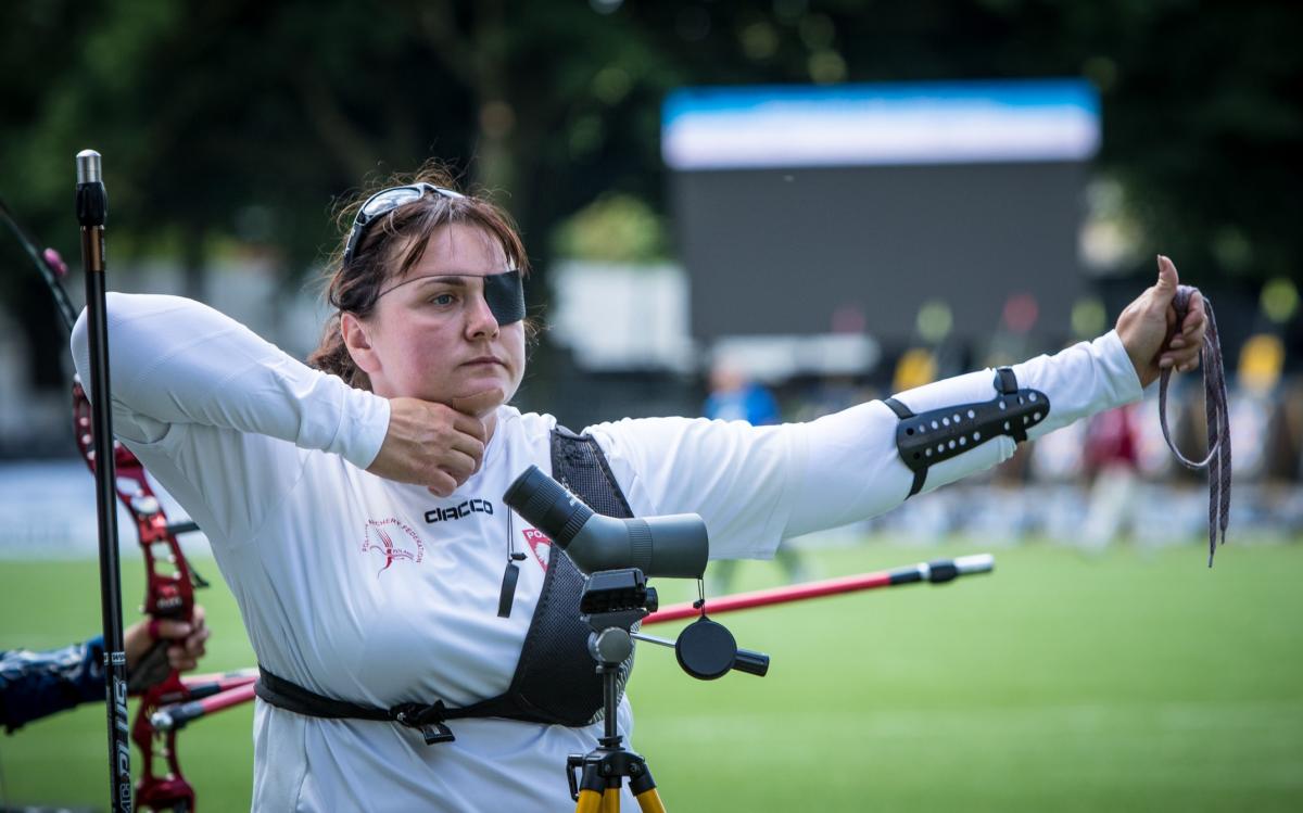 Polish woman with eye patch looks on after shooting her arrow