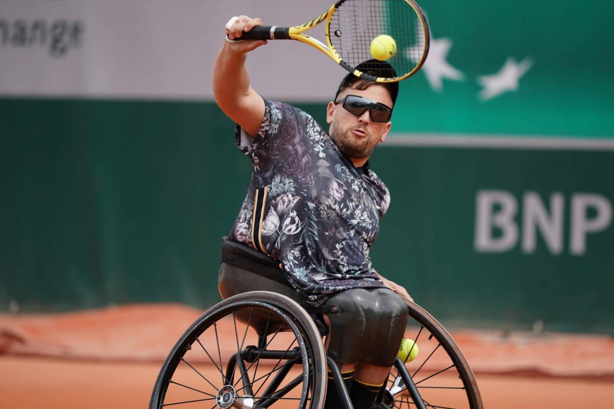 male wheelchair tennis player Dylan Alcott hits a backhand on a clay court