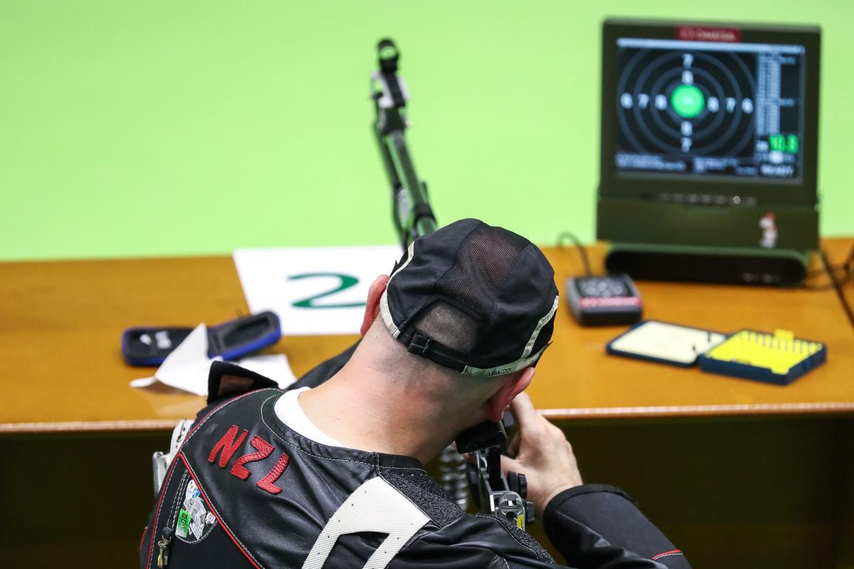 A man seated seen from behind while shooting with a rifle