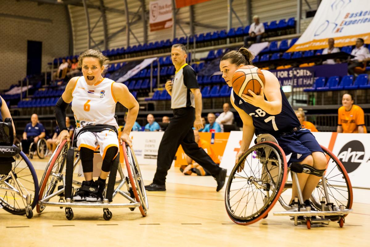 Helen Freeman and Jitske Visser - wheelchair basketball British female wheelchair basketball player makes a move with the ball while a Dutch player turns to defend her