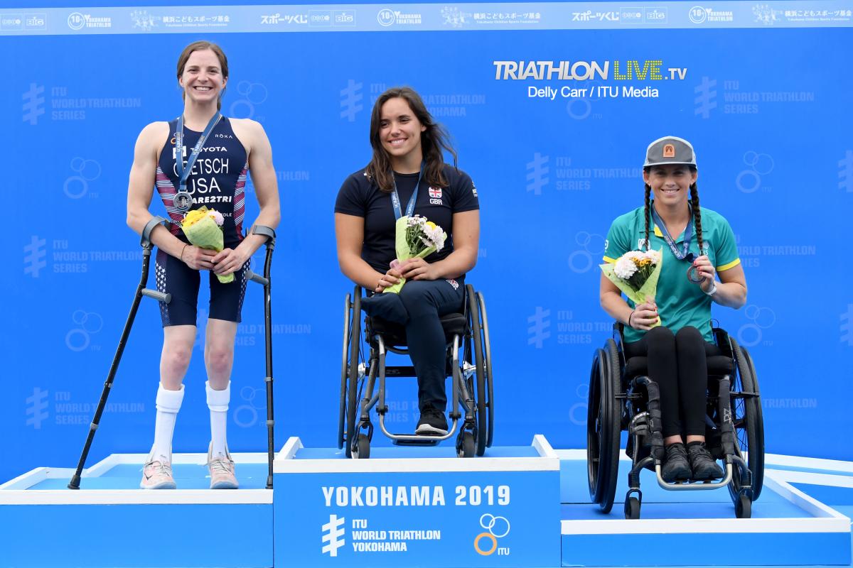 Three female triathletes on a podium smiling