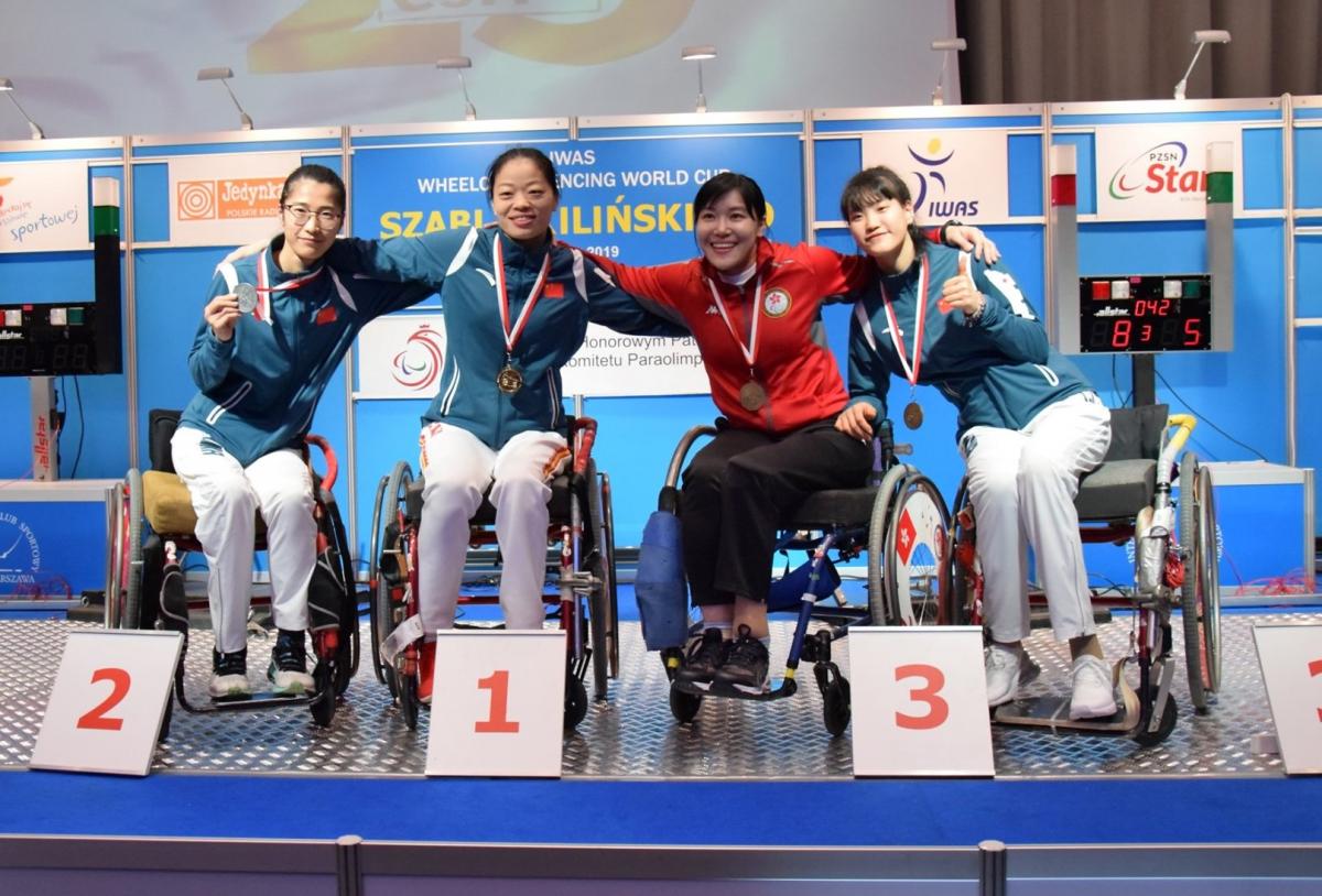 Xufeng Zou - Yu Chui Yee - Jing Rong - Haiyan Gu - wheelchair fencing Four female wheelchair fencers put arms around each other and pose on a podium
