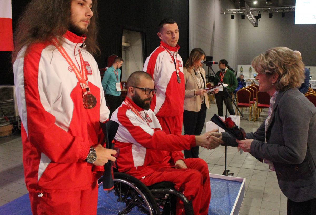 Filip Rodzik - Poland - shooting Man in wheelchair shakes hand with woman during medal ceremony