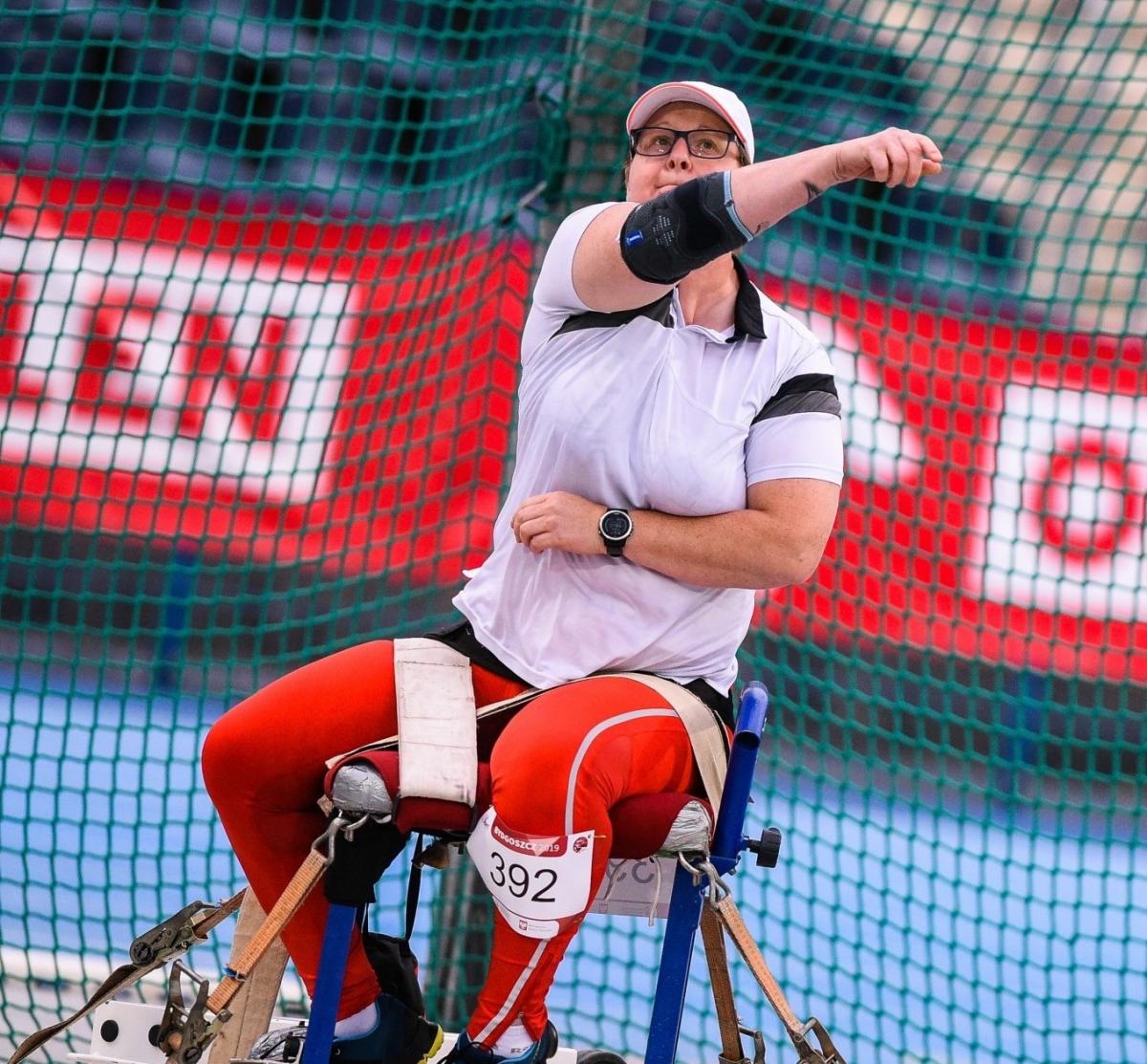 Polosh woman sits in chair and throws a discus