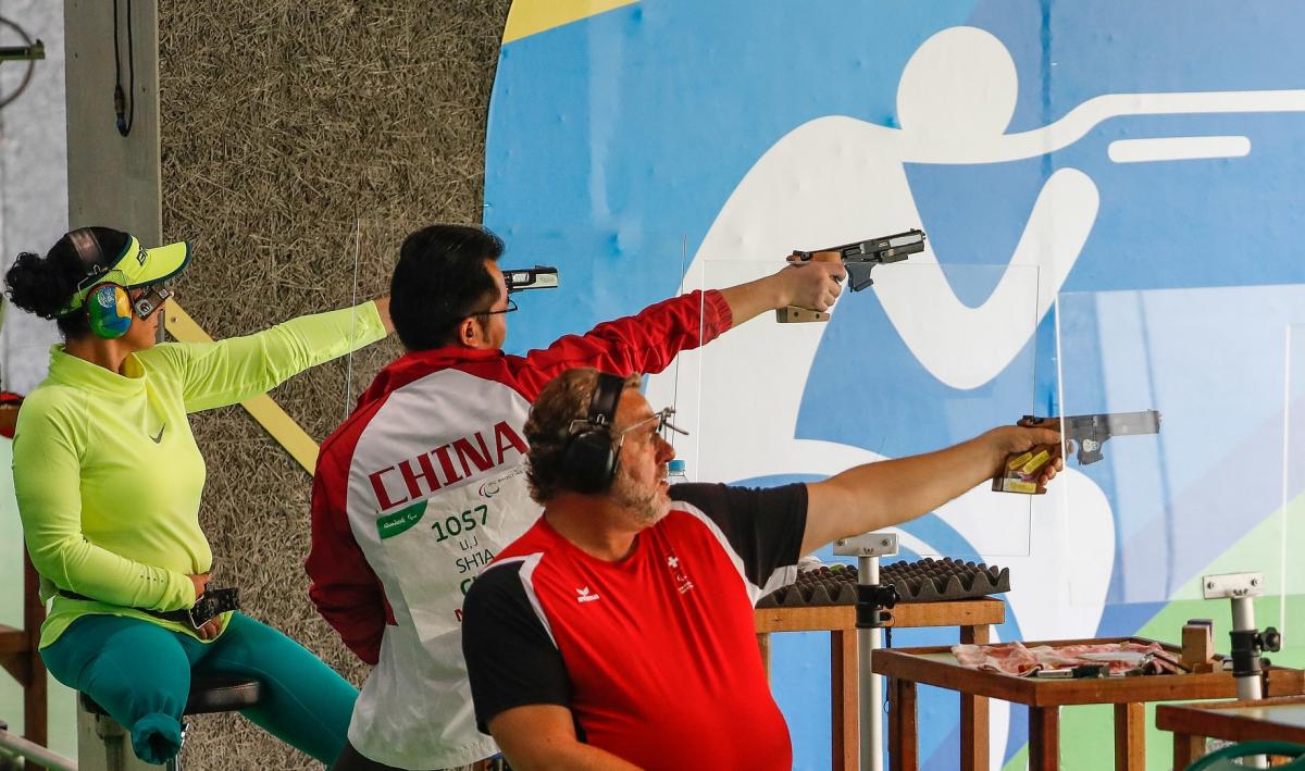 A one-legged woman and two men competing at a shooting range