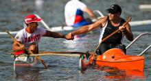 A picture of 2 men in a canoe shaking their hands celebrating a victory