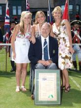 A picture of a man in a wheelchair and 3 girls standing next to him posing for a picture