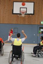 A picture of a young person in a wheelchair shooting a basket ball.