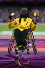 A picture of a man in a wheelchair showing his gold medal
