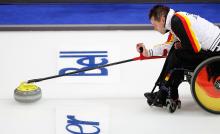 A picture of a man in a wheelchair playing Curling