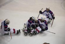 A picture of men sitting in a sledge celebrating their victory in a hockey match.