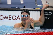 A picture of a woman in the pool holding the starting block with her hand