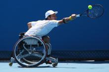 A picture of a man in a wheelchair playing a backhand during a wheelchair tennis match