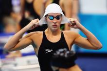 A picture of a woman putting the swimming cap on her head