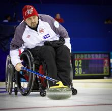 A picture of a man in a wheelchair playing curling