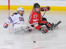 A picture of two mens in sledges fighting for the puck during a hockey match