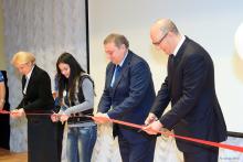 A picture of 4 person cutting a red ribbon 