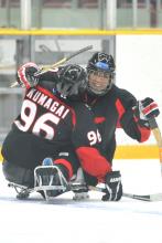 A player in a sledge playing ice hockey and celebrating their victory