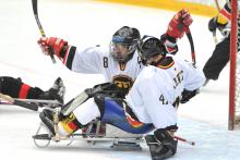 A picture of 2 men in sledges celebrating a goal during a ice sledge hockey match