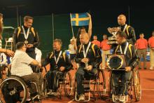 A picture of men in wheelchairs receiving their medals during a medal ceremony