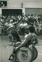 A picture of 3 men in a wheelchair playing basketball