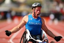 An wheelchair racer shouts out after crossing the finish line in first place.