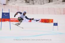 Man in sit ski doing a jump on the slope