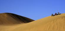 White jeeps driving up a sand dune