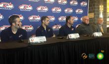 Three players and two men in training suits on a podium