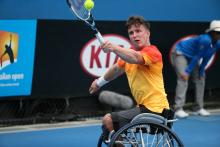 Man in wheelchair, hitting a ball with a tennis racket