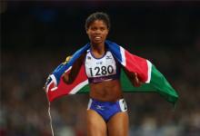 A picture of a woman running with a Namibian flag on her shoulder 