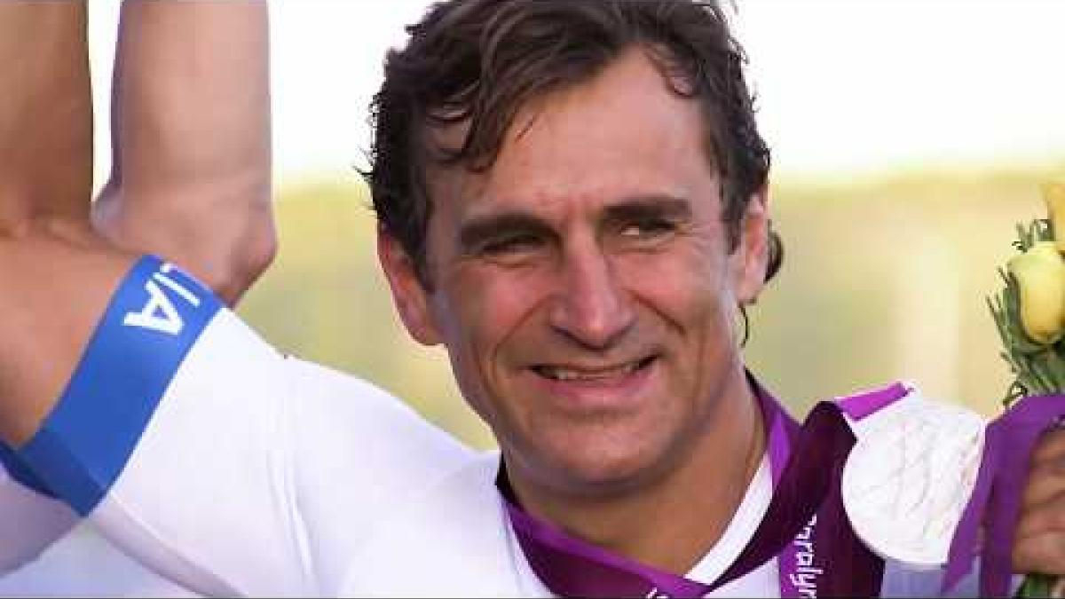Video Thumbnail of a male Para cycling athlete celebrating and holding up a silver medal. 